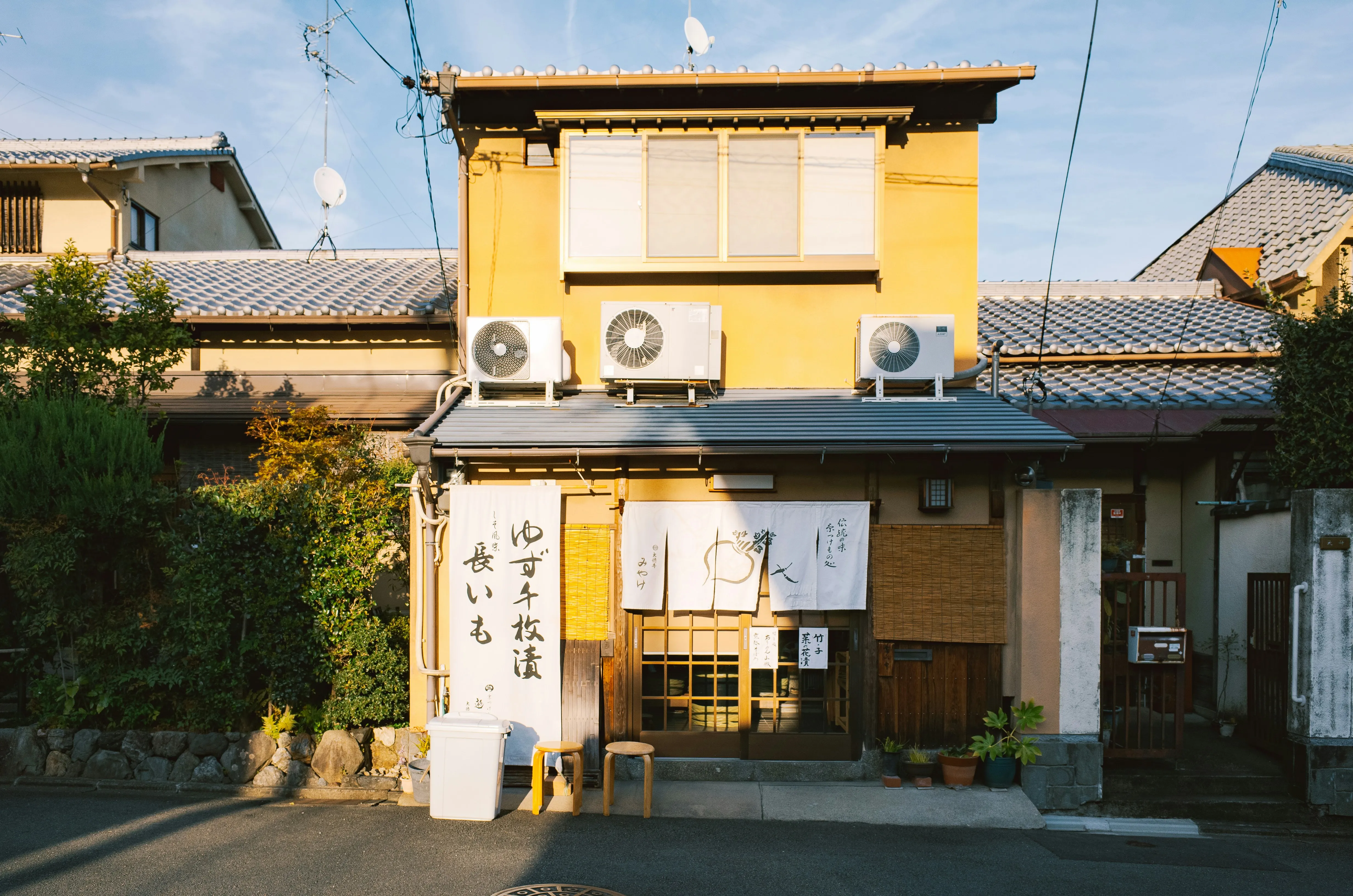 Yellow Japanese building with air conditioners and curtains and signs